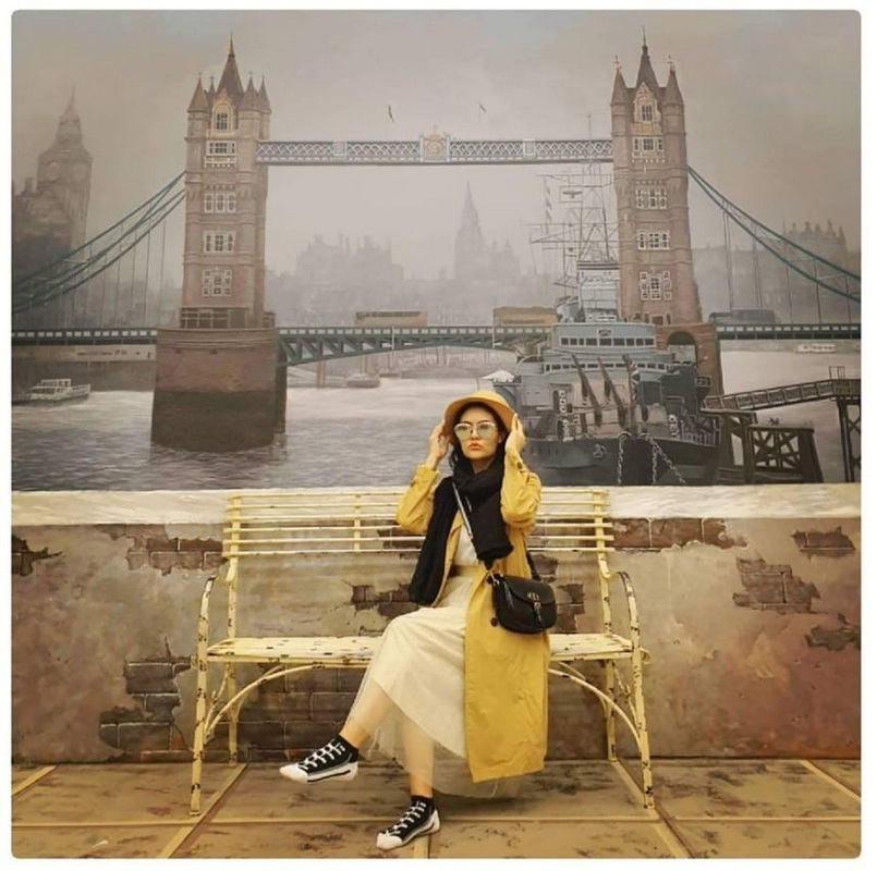 Indoor Murals of Tower Bridge at Art in Paradise Chiang Mai Woman sitting on a bench with Tower Bridge mural in the background at Art in Paradise Chiang Mai.