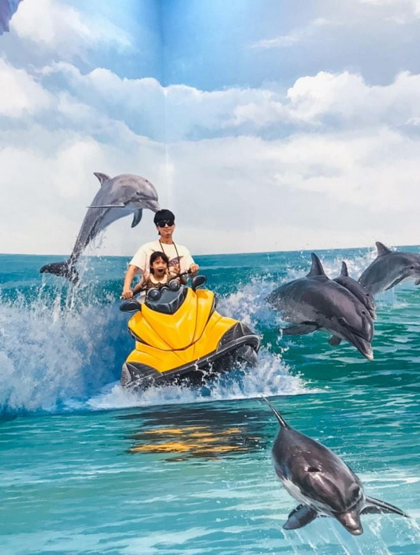 Dolphins and Jet Ski Adventure at Chiang Mai Art in Paradise Person and child riding a yellow jet ski with dolphins jumping nearby in the ocean at Chiang Mai Art in Paradise.