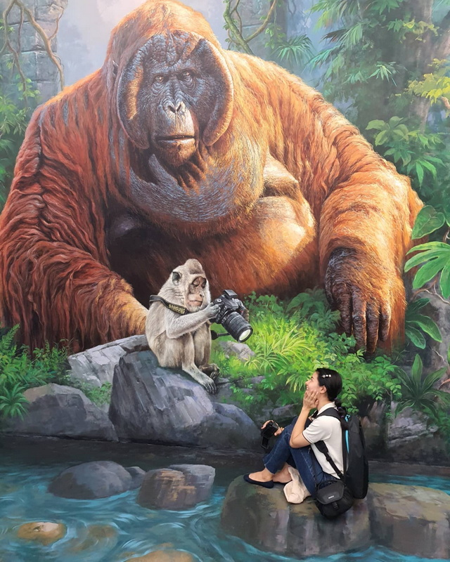 Jungle Mural with Woman at Chiang Mai Art in Paradise Woman sitting on rock in front of jungle mural with orangutan and monkey holding camera at Chiang Mai Art in Paradise.