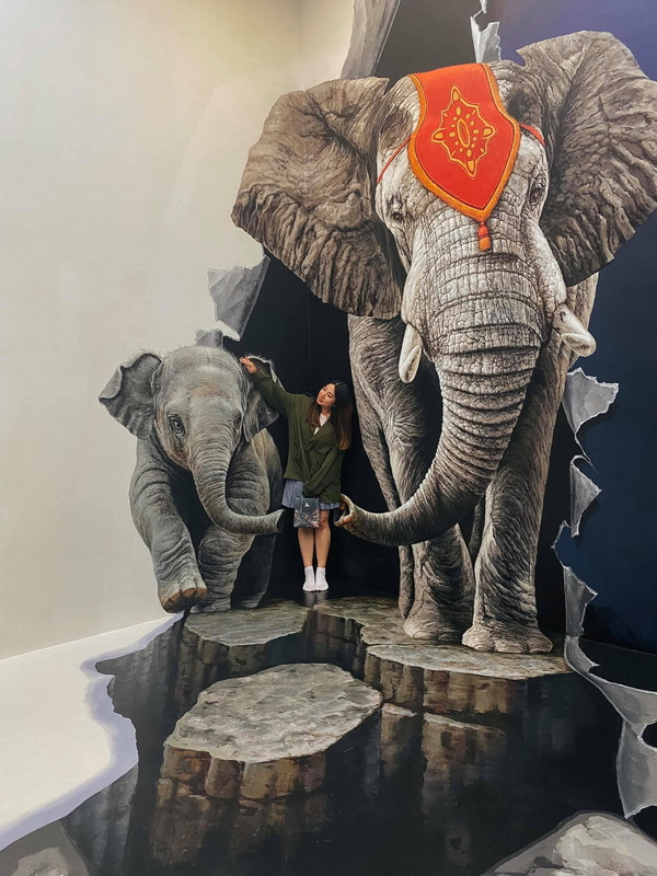 Elephants Art Display at Art in Paradise Chiang Mai Woman touching elephant trunks in indoor animal-themed art display at Art in Paradise Chiang Mai.