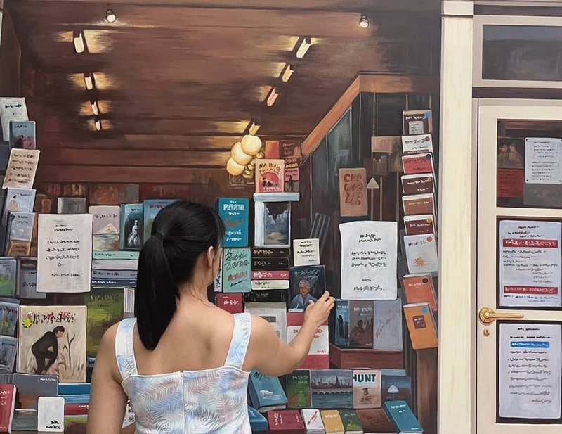 Woman Viewing Book Display at Chiang Mai Art in Paradise Woman browsing books and posters in an indoor display area at Chiang Mai Art in Paradise.