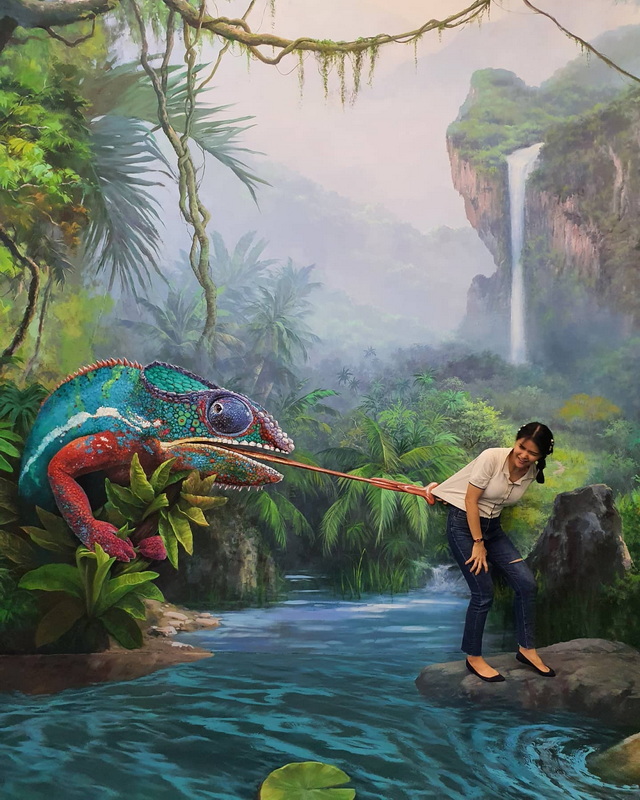 Jungle Mural Scene at Chiang Mai Art in Paradise Woman pulling a painted colorful chameleon on a jungle mural background with waterfall at Chiang Mai Art in Paradise.
