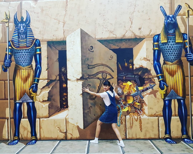 Egyptian Statue Scene at Chiang Mai Art in Paradise Girl standing in front of Egyptian-themed statues and wall carvings at an amusement park at Chiang Mai Art in Paradise.