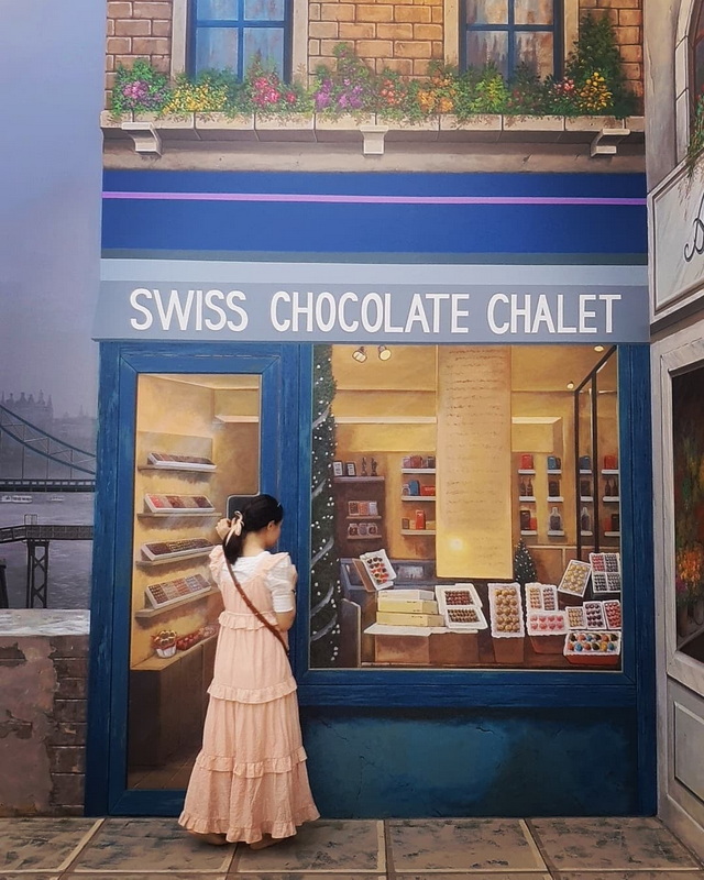 Chocolate Shopfront Window at Chiang Mai Art in Paradise Girl in pink dress looking at chocolate displays inside a shopfront at Chiang Mai Art in Paradise.