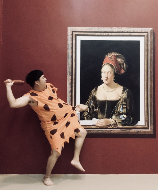 Person with Portrait in Gallery at Chiang Mai Art in Paradise Person striking a pose next to a classical portrait painting in an art gallery at Chiang Mai Art in Paradise.