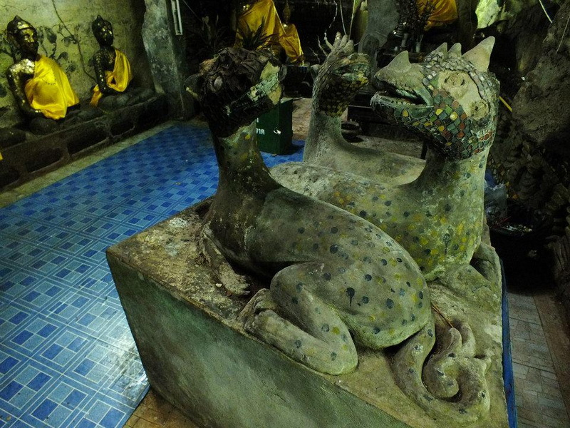 Dragon Sculptures Inside a Cultural Room at Chiang Dao Cave Stone dragon sculptures with mosaic eyes inside a room with Thai statues in the background at Chiang Dao Cave.