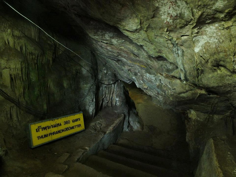 Cave Interior with Sign and Stairs at Chiang Dao Cave Inside a cave with rocks, stairs, and a yellow sign with text at Chiang Dao Cave.
