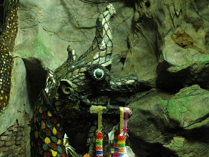 Close-up of a metallic mosaic dragon sculpture inside a cave with rocky walls at Tham Chiang Dao.