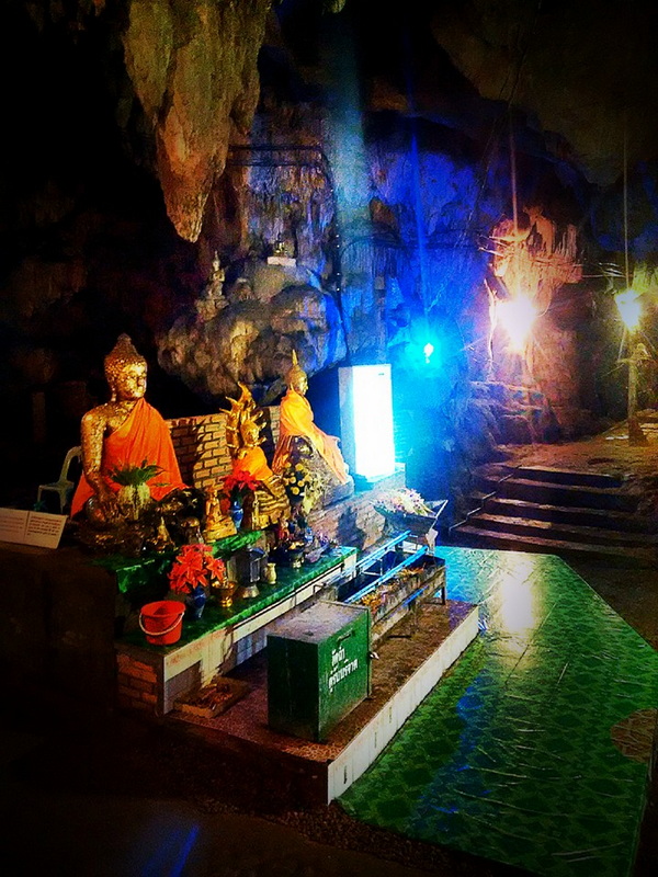 Temple Inside a Cave at Tham Chiang Dao Buddha statues in orange robes inside a cave with colorful lighting effects at Tham Chiang Dao.