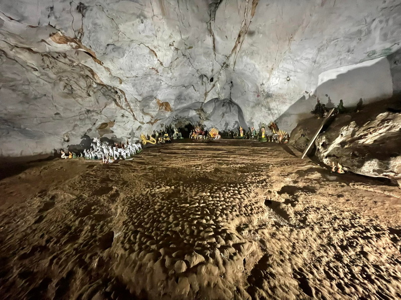 Inside a Cave at Mueang On Cave Interior of a cave with textured ground and small statues along the sides at Mueang On Cave.