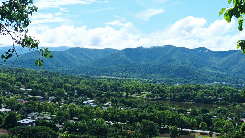 Scenic Mountain and Village View at Mueang On Cave Wide landscape view of green mountains, river, and village under a partly cloudy sky at Mueang On Cave.