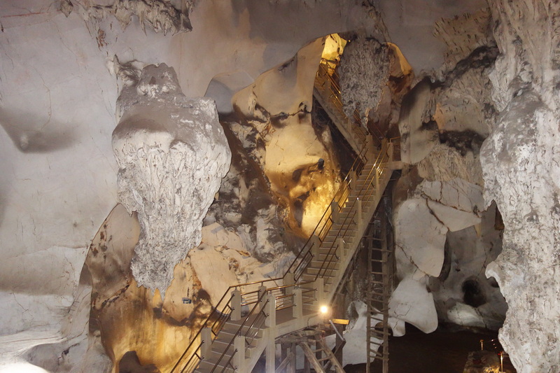 Indoor view of a cave with uneven rocks and a metal staircase leading upwards at Mueang On Cave.