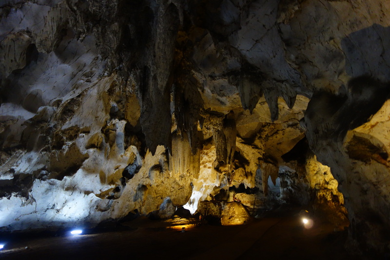 Inside a cave with rock formations and artificial lighting illuminating the ceiling and floor at Mueang On Cave.