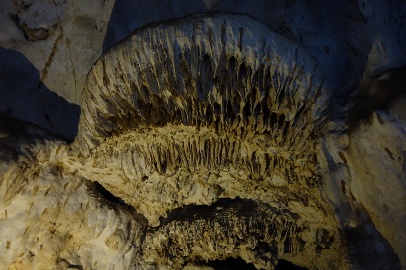 Close-up of cave ceiling with stalactites and rock formations visible in darkness at Mueang On Cave.