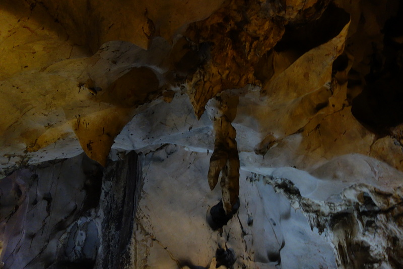 View of stalactites and stalagmites inside a limestone cave with rough rocky walls at Mueang On Cave.