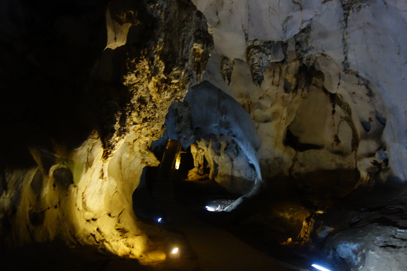 Dark cave interior with a staircase lit by small lights along the path at Mueang On Cave.