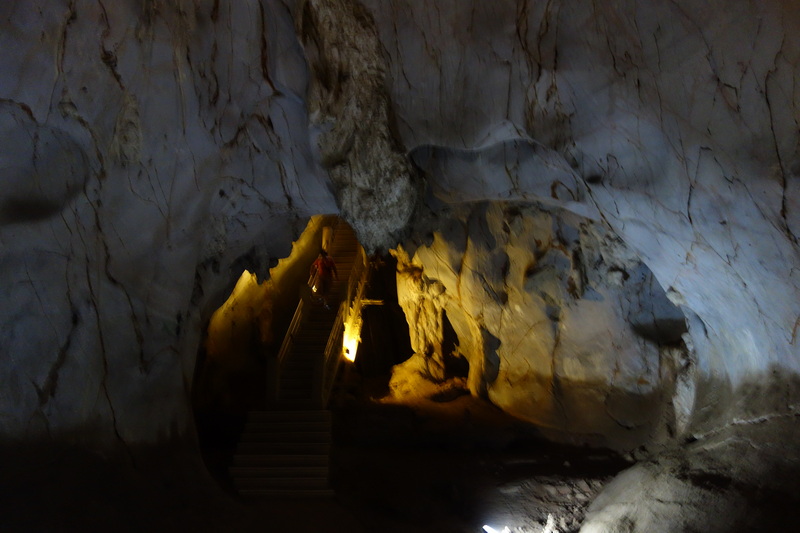 Inside a limestone cave with stairs and warm lights illuminating rock formations at Mueang On Cave.