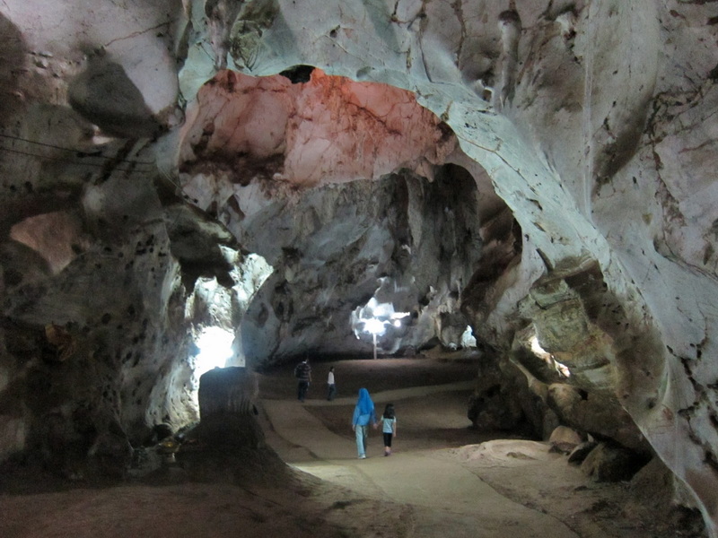 Visitors exploring a spacious, illuminated cave with natural rock formations at Muang On Cave.