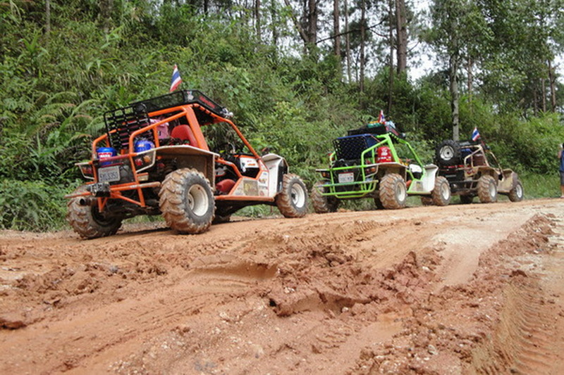 Three off-road vehicles parked on a dirt trail amidst green trees and foliage at ATV tour Chiang Mai.