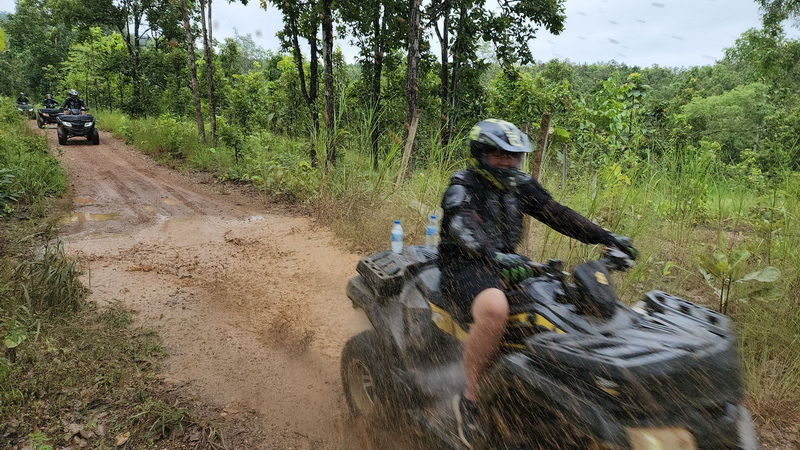 Person riding an ATV on a muddy trail through a forested area at Chiang Mai atv tour.