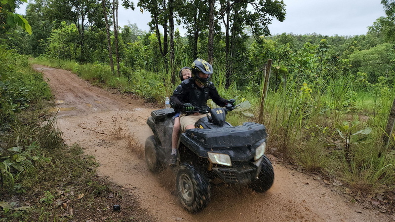Person riding an ATV with a passenger through a lush forest trail at Chiang Mai atv tour.