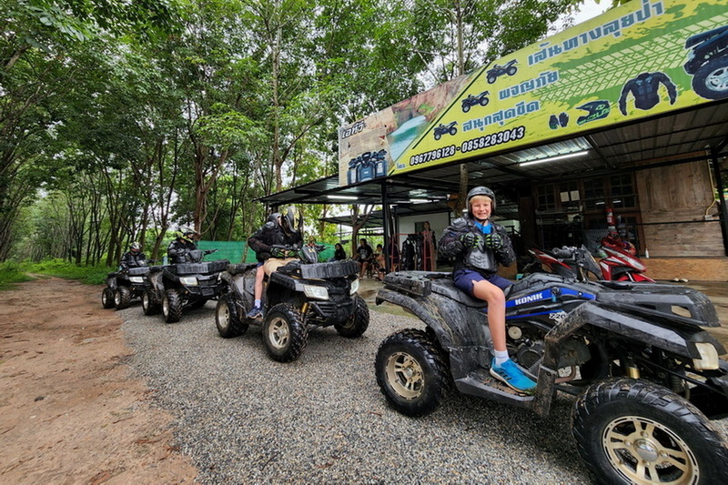 People sitting on ATVs in front of a shop surrounded by trees in a forest setting at Chiang Mai atv tour.