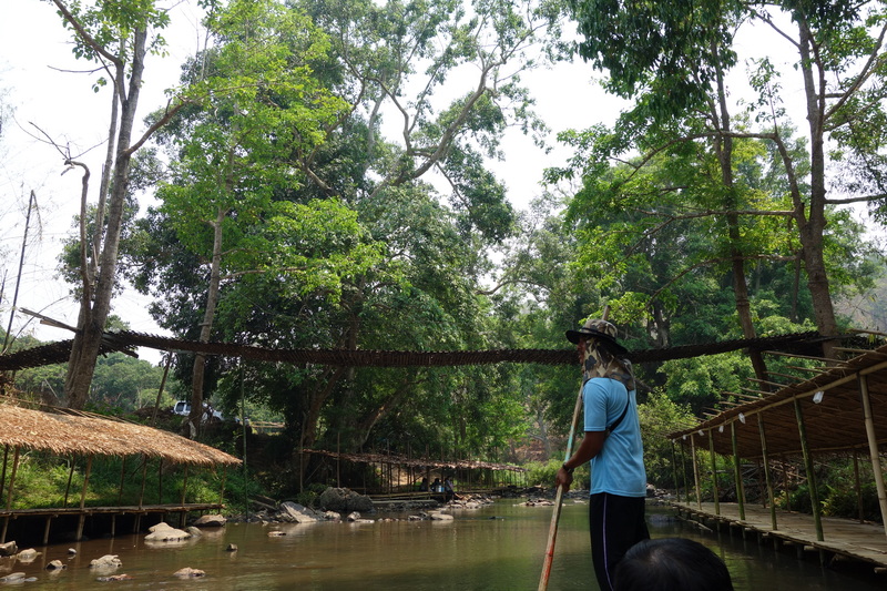 Person standing on wooden platform over river with dense green forest around at Rafting in Mae Wang.