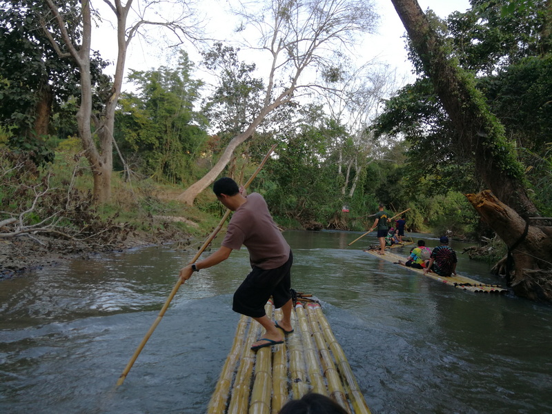 Bamboo Rafting Adventure at Bamboo Rafting in Mae Wang People paddling bamboo rafts down a peaceful river in a forested area at Bamboo Rafting in Mae Wang.