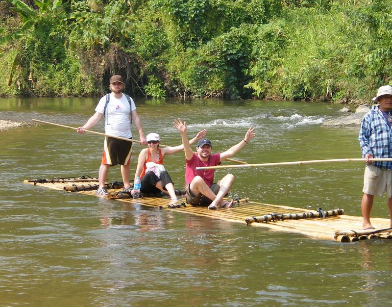 People enjoying bamboo rafting on a river surrounded by dense greenery at Rafting in Mae Wang.