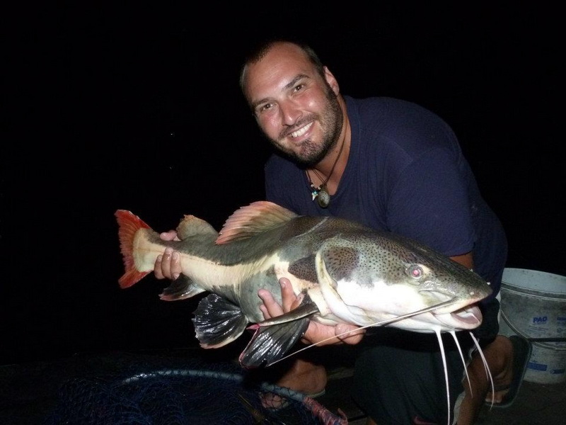Night Fishing Success at Chiang Mai Fishing Man holding a big fish in his hands during nighttime fishing activity at Chiang Mai Fishing.