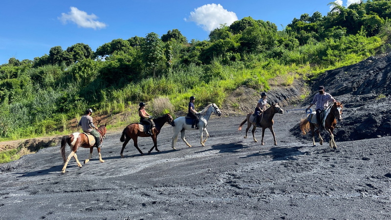 Six riders on horses walking along a gravel trail with lush greenery behind them at Horse Riding Chiang Mai.