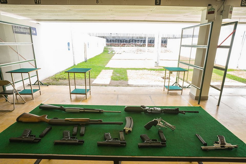 Collection of rifles and handguns displayed on a green surface in a shooting range at Chiang Mai Shooting Range.