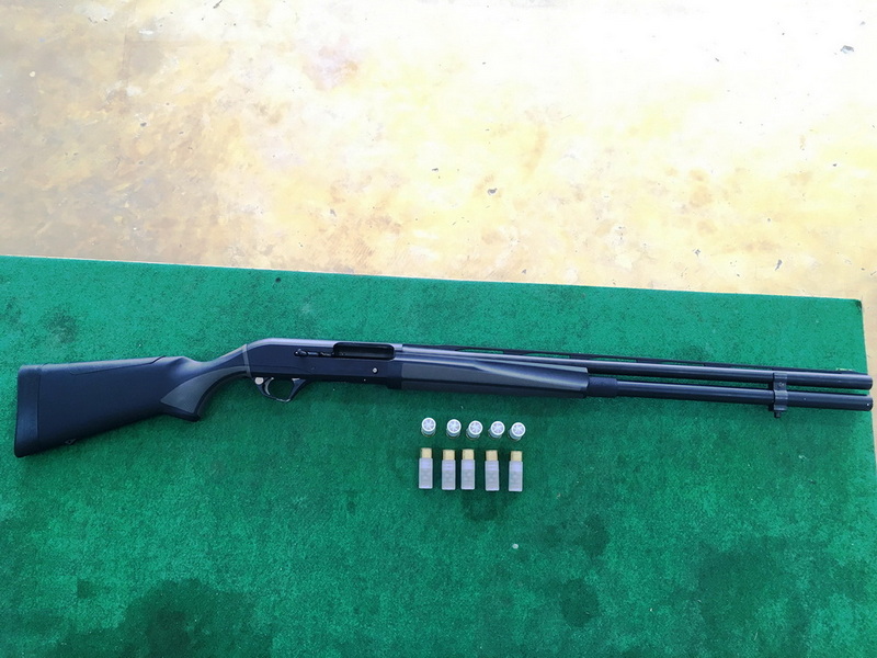 Black air rifle with pellets and small objects on green surface at Chiang Mai Shooting Club.