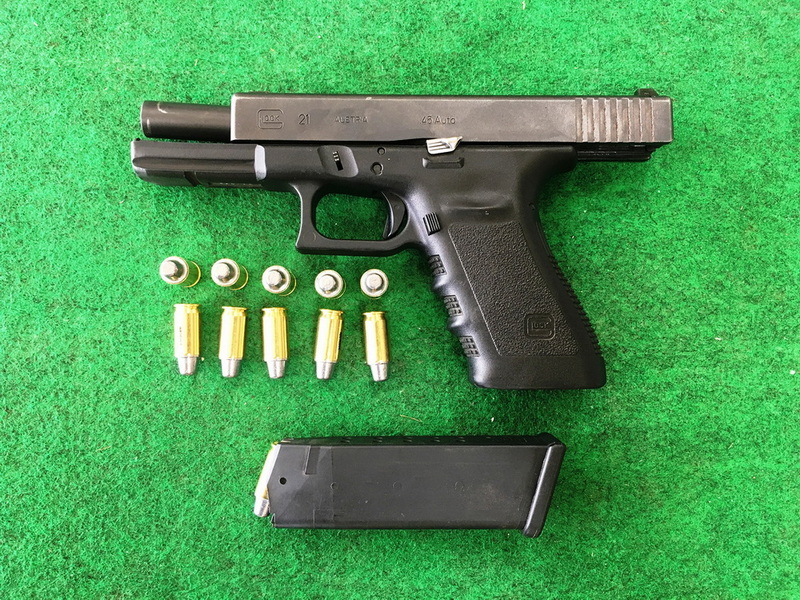 Firearm and Ammunition Layout at Chiang Mai Shooting Range Black pistol with bullets and magazine on green surface at Chiang Mai Shooting Range.