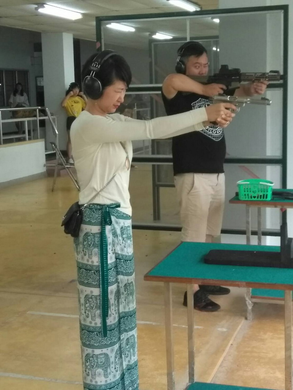 Woman and man aiming rifles at indoor shooting range with ear protection at Chiang Mai Shooting Range.