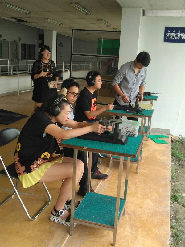 People aiming firearms at targets indoors with ear protection in a shooting range at Chiang Mai Shooting Range.