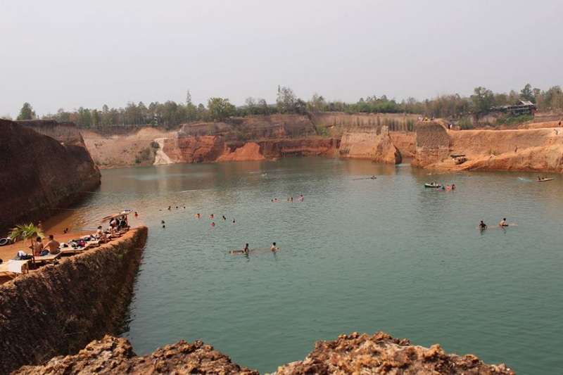 People swimming and relaxing in a small water body with cliffs around it at Grand Canyon Chiang Mai.
