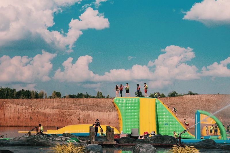 Children playing on a colorful inflatable water slide on a sandy beach under blue sky at Grand Canyon Chiang Mai.