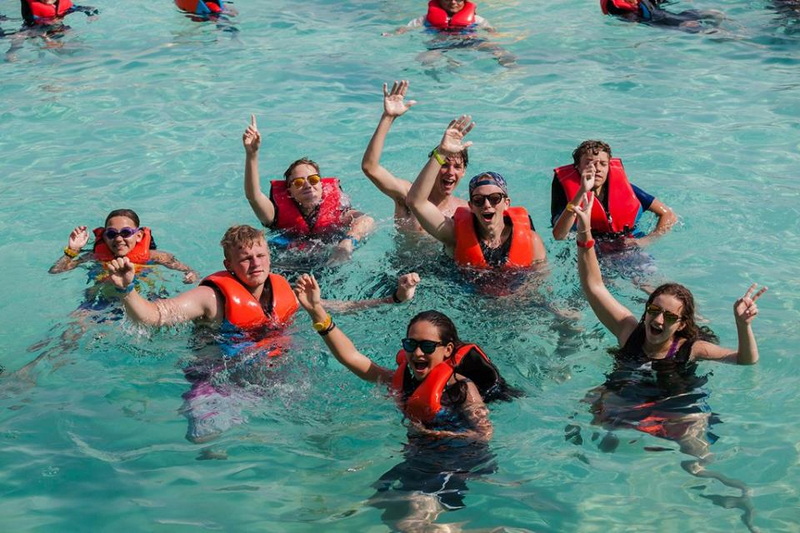 Children Swimming and Waving at Tube Trek Water Park Children in orange life jackets enjoying and waving in a clear blue swimming pool at Tube Trek Water Park.