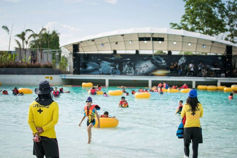 Outdoor Pool Scene with Swimmers at Tube Trek Water Park People enjoying swimming and playing in a large outdoor pool under a stage area at Tube Trek Water Park.