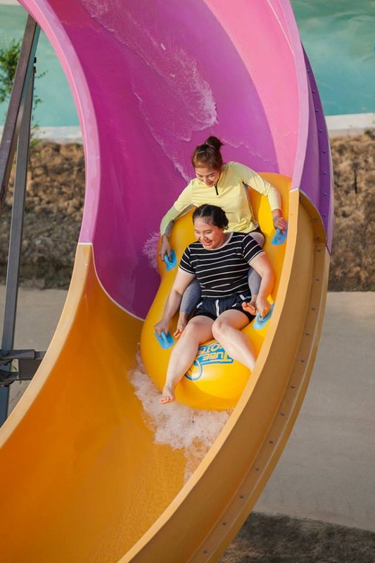 Girls on Water Slide at Tube Trek Water Park Two girls sliding down a colorful water slide with pink cover at a water park at Tube Trek Water Park.