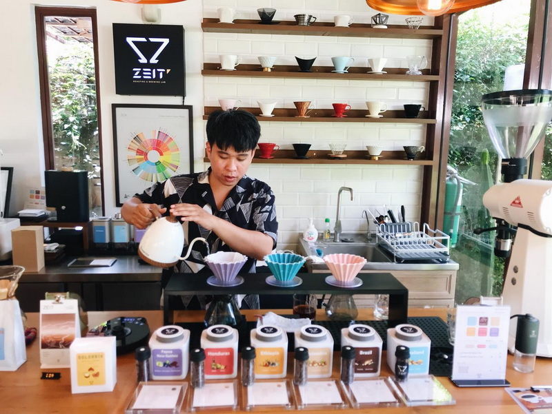 Coffee Preparation in a Cafe at Coffee Farm Tour Chiang Mai A barista pours hot water into coffee drippers in a cozy cafe setting at Coffee Farm Tour Chiang Mai.