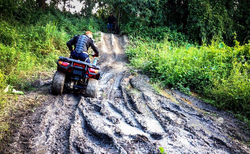 Person riding ATV on muddy trail with lush greenery around at Huay Tung Tao.