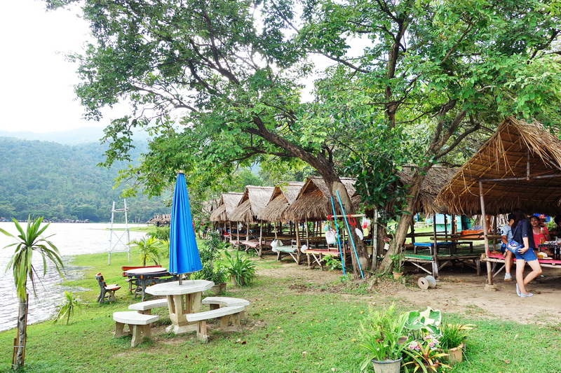 Lakeside scene with thatched-roof pavilions and trees by the water at Huay Tung Tao.