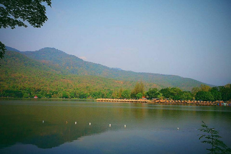 Serene lake with mountains and trees reflecting on the water at Huay Tung Tao Chiang Mai.