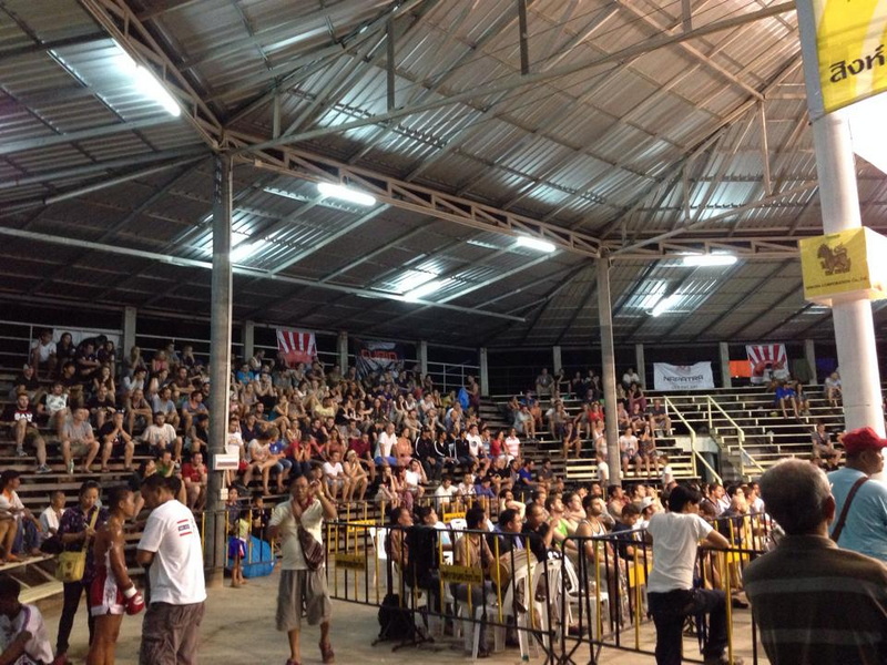 Indoor Arena with Spectators at Kalare Boxing Stadium Crowded indoor arena with spectators sitting under a metal roof and bright lights at Kalare Boxing Stadium.