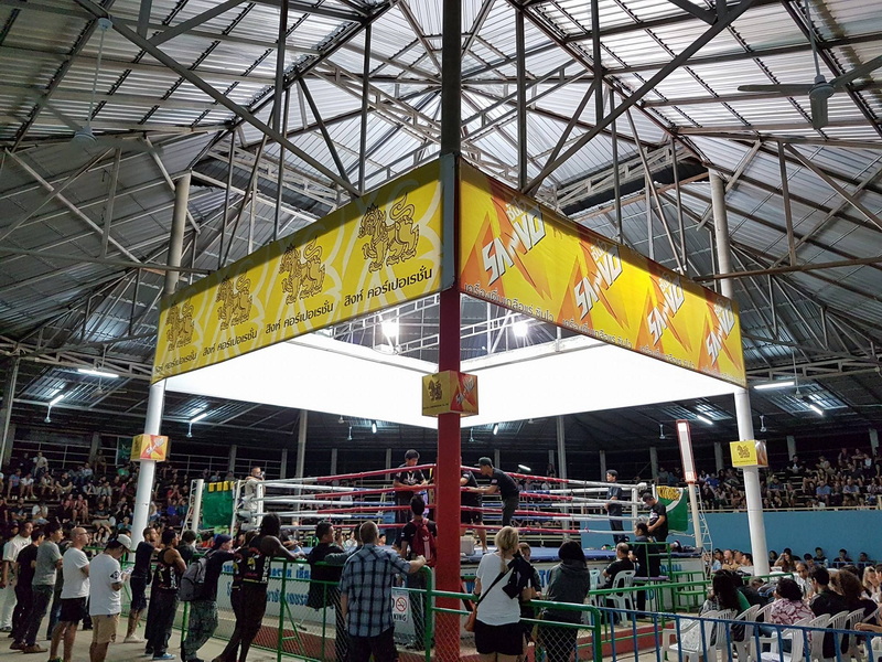 Indoor boxing ring surrounded by spectators and a large overhead banner at Kalare Boxing Stadium.