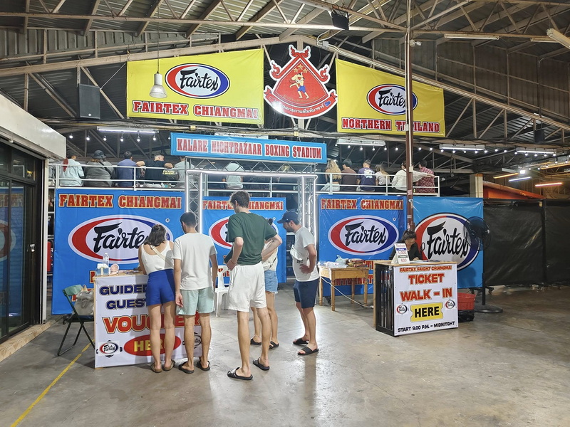 People queue at ticket booth with banners for boxing stadium at Kalare Boxing Stadium.