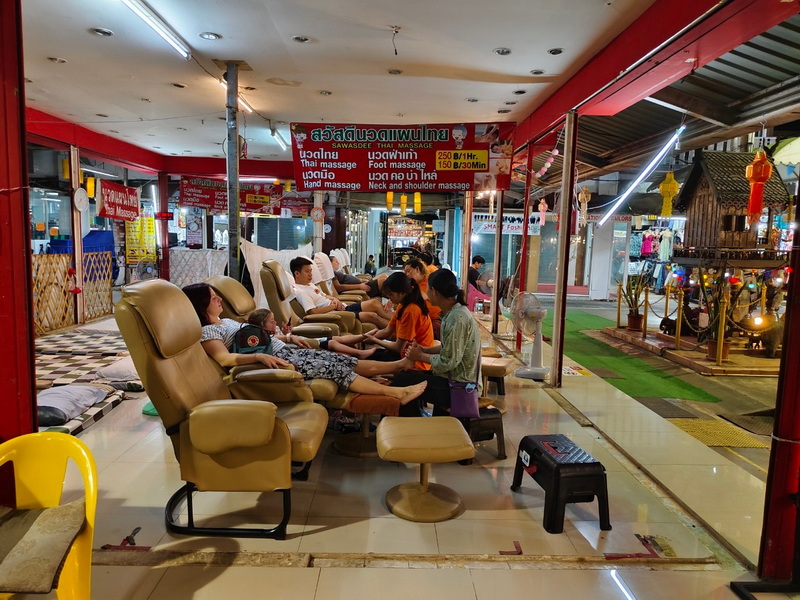 People receiving foot massages inside a shop with reclining chairs and staff at Chiang Mai Night Market Food Guide.