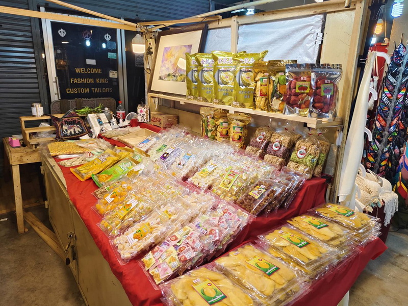Market Snack Stand at Top Night Markets In Chiang Mai Market stall with packaged dried fruits, snacks, and artwork behind the display at Top Night Markets In Chiang Mai.